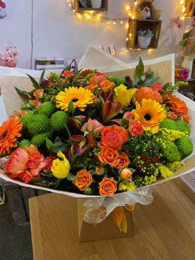 Horizon - A vibrant handtied in water presented in a gift box, created using the fresh blooms of the day in orange, yellow and white with complementary foliage.